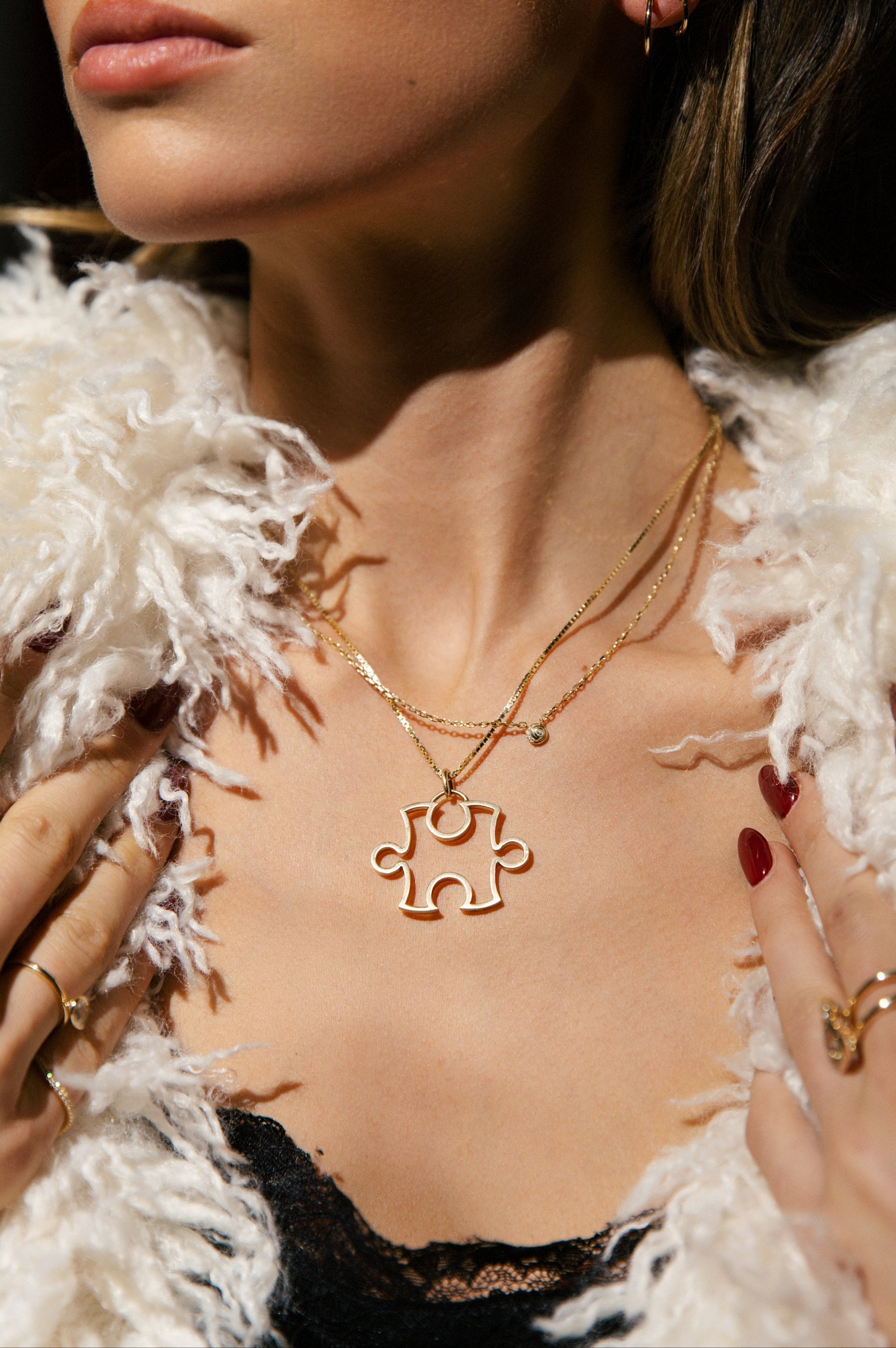 Close-up of a person wearing gold necklaces with a unique puzzle pendant