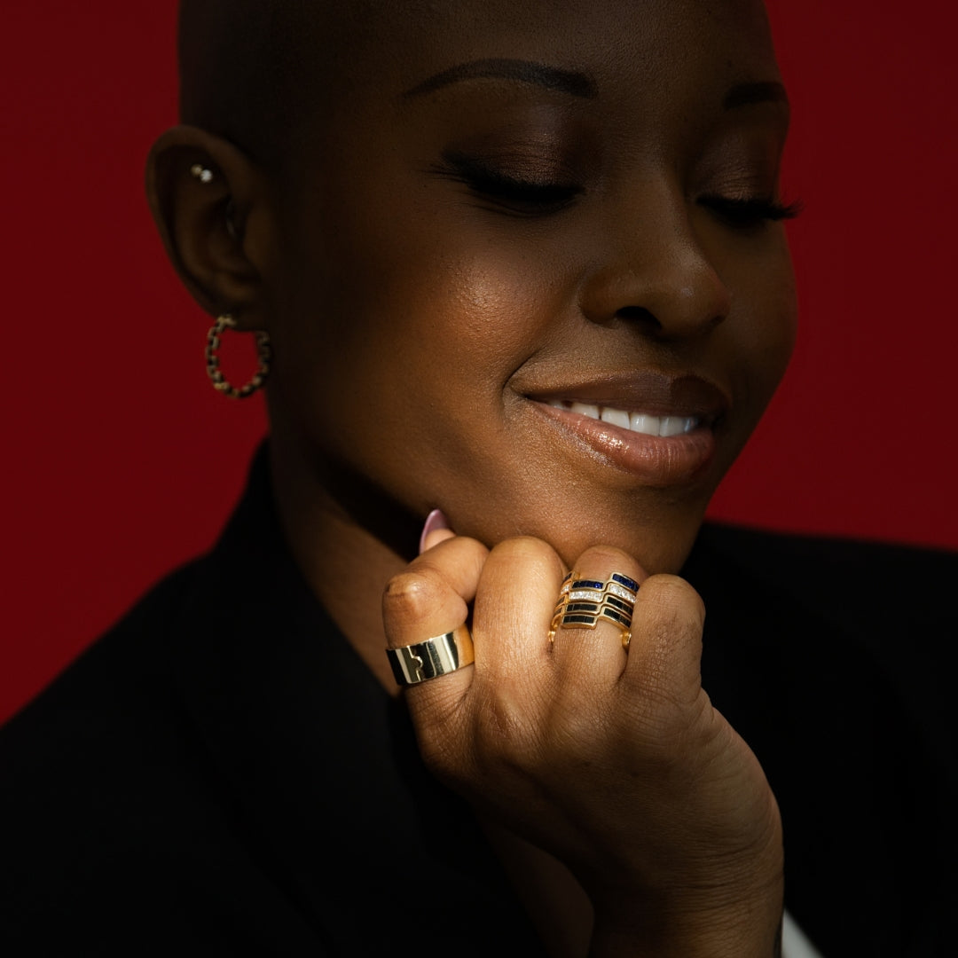 Close-up of a person wearing Bound By Love 14k gold rings with a red background Bondeye Jewelry