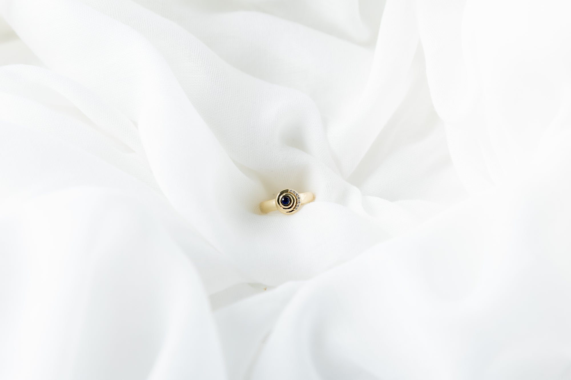 Khushi Ring in 14K yellow gold with spiral design and white diamonds and blue sapphires