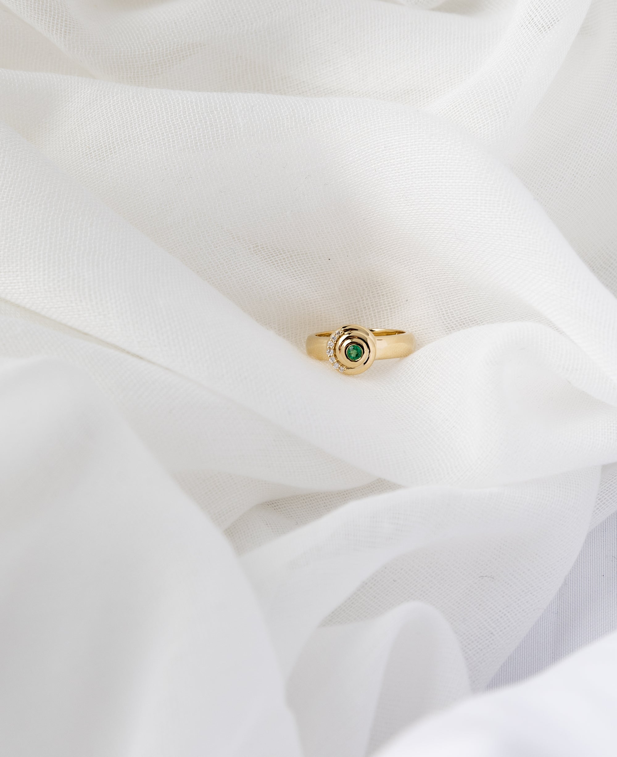 Khushi Ring in 14K yellow gold with spiral design and white diamonds and emerald
