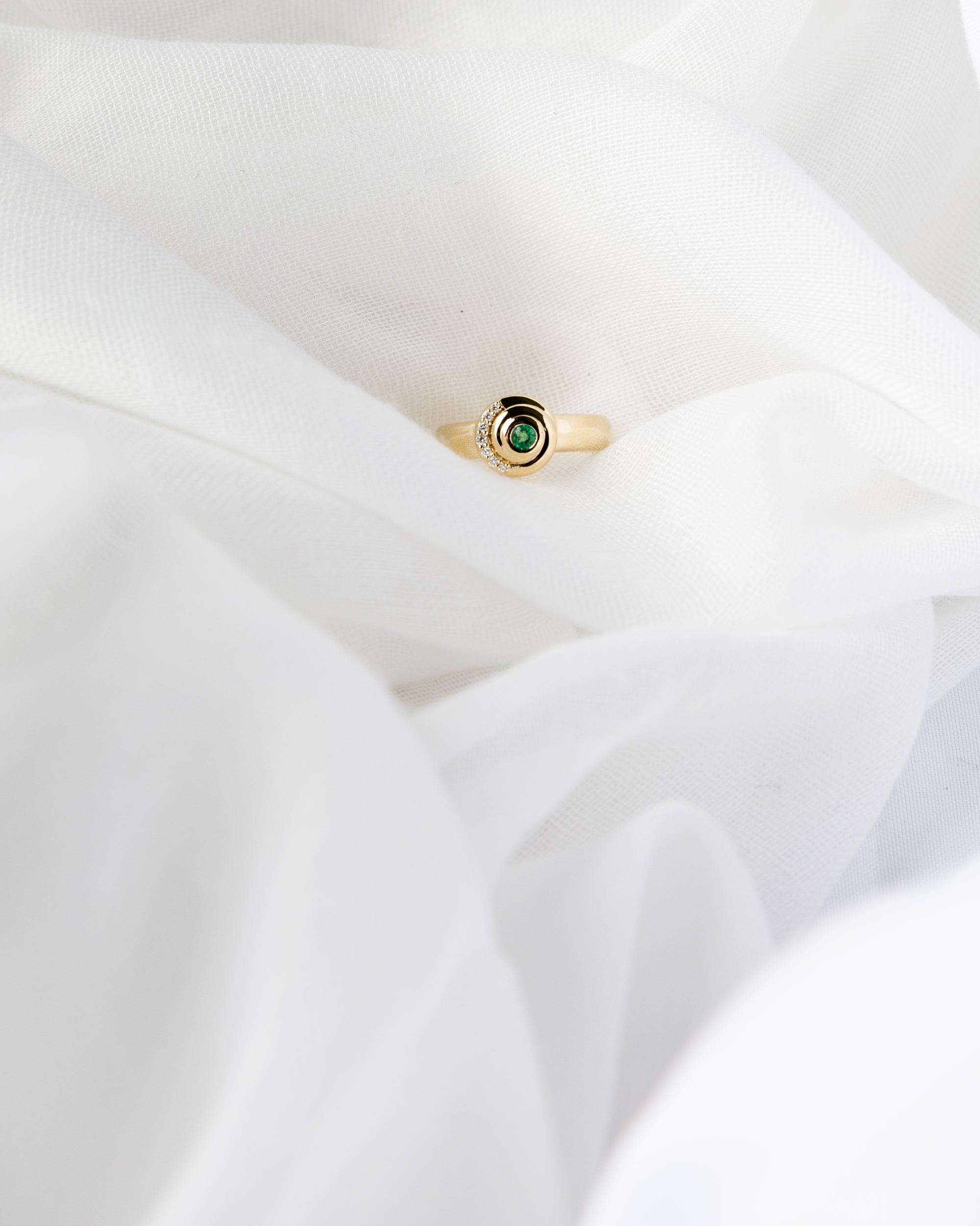 Khushi Ring in 14K yellow gold with spiral design and white diamonds and emerald