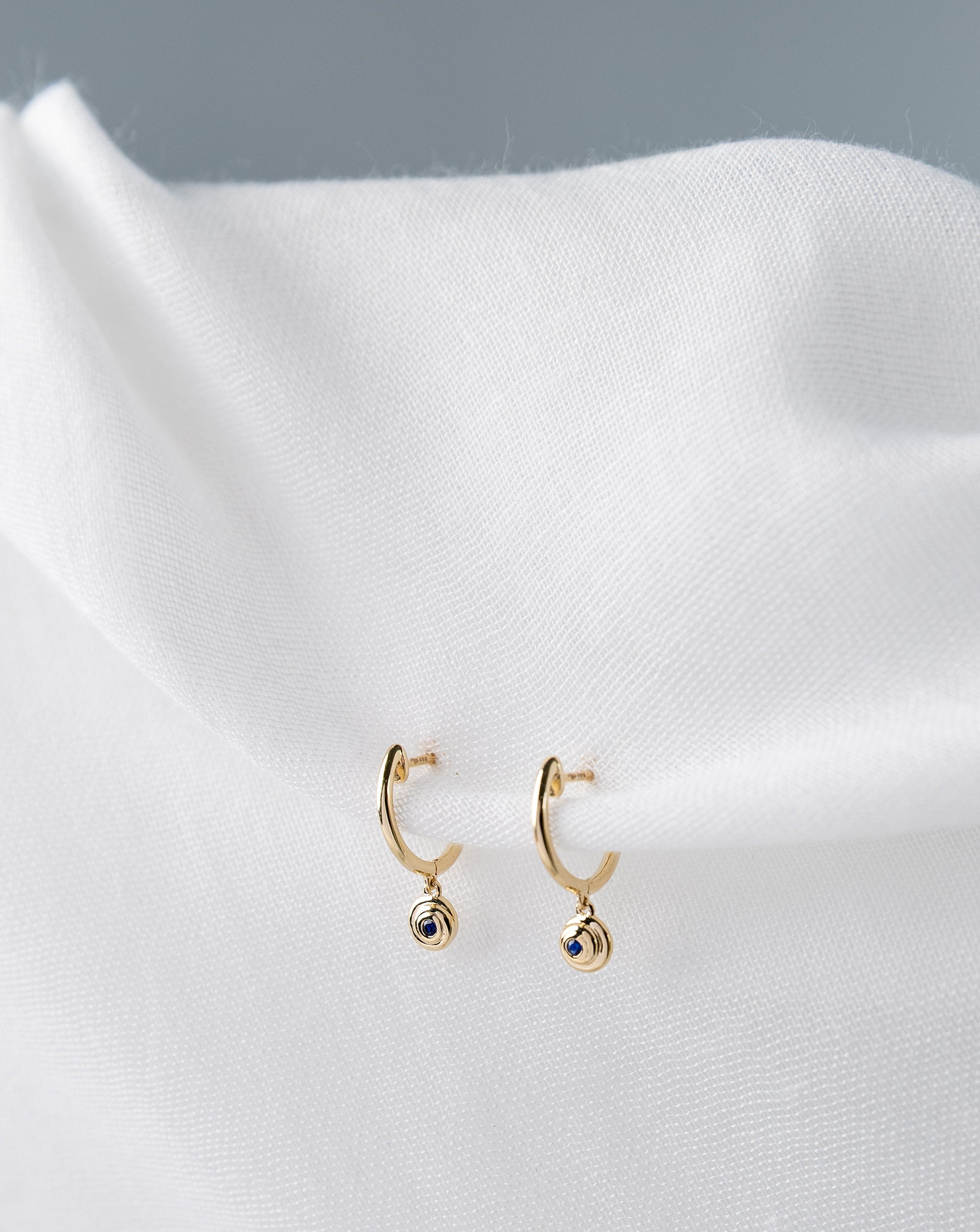 Lucy Huggies in 14K yellow gold with blue sapphires spiral design