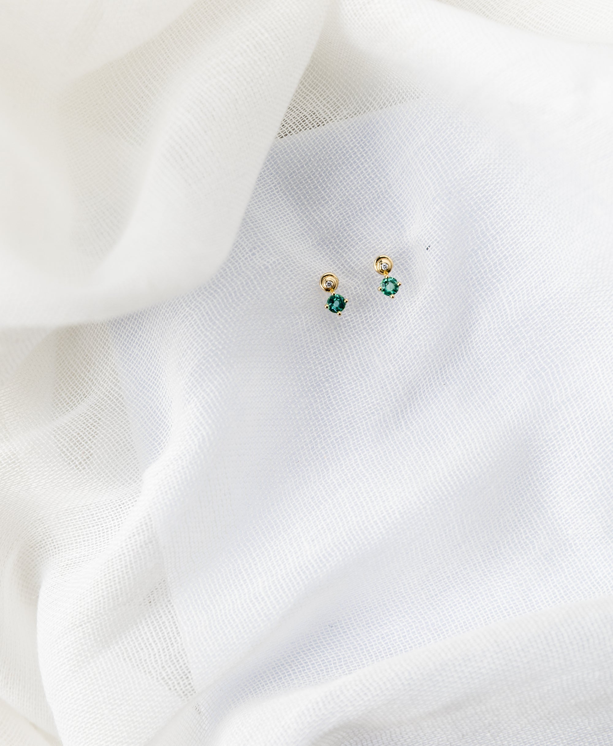 Spiral gold stud earrings with white diamonds and emeralds